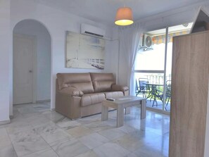 A living room with a sofa, a coffee table, and a balcony with outdoor furniture. - Two-Bedroom Apartment with Terrace and Sea Views near the Centre (Torremolinos)