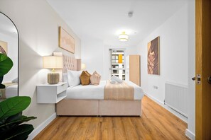 Quarto moderno com cama, mesas de cabeceira, abajur e um espelho grande.