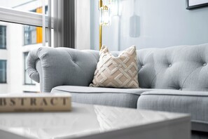 Ein modernes Wohnzimmer mit einem grauen Sofa, einem beigen Kissen und einem weißen Couchtisch.