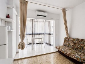 A modern living room with a sofa, a dining table, and a kitchen area with a refrigerator. - Studio with A/C and WiFi in Central Torremolinos, 15 Minutes from the Beach (Torremolinos)