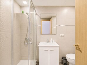 A modern bathroom with a glass shower enclosure, a white sink with a mirror above, and a toilet. - Studio with A/C and WiFi in Central Torremolinos, 15 Minutes from the Beach (Torremolinos)