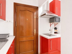 A kitchen with a wooden door, a microwave, and red cabinets. - Studio with A/C and WiFi in Central Torremolinos, 15 Minutes from the Beach (Torremolinos)