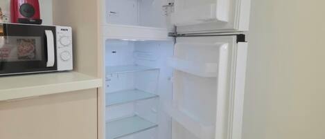 Une cuisine équipée d’un four à micro-ondes, d’un réfrigérateur et d’un appareil de couleur rouge posé sur le plan de travail.