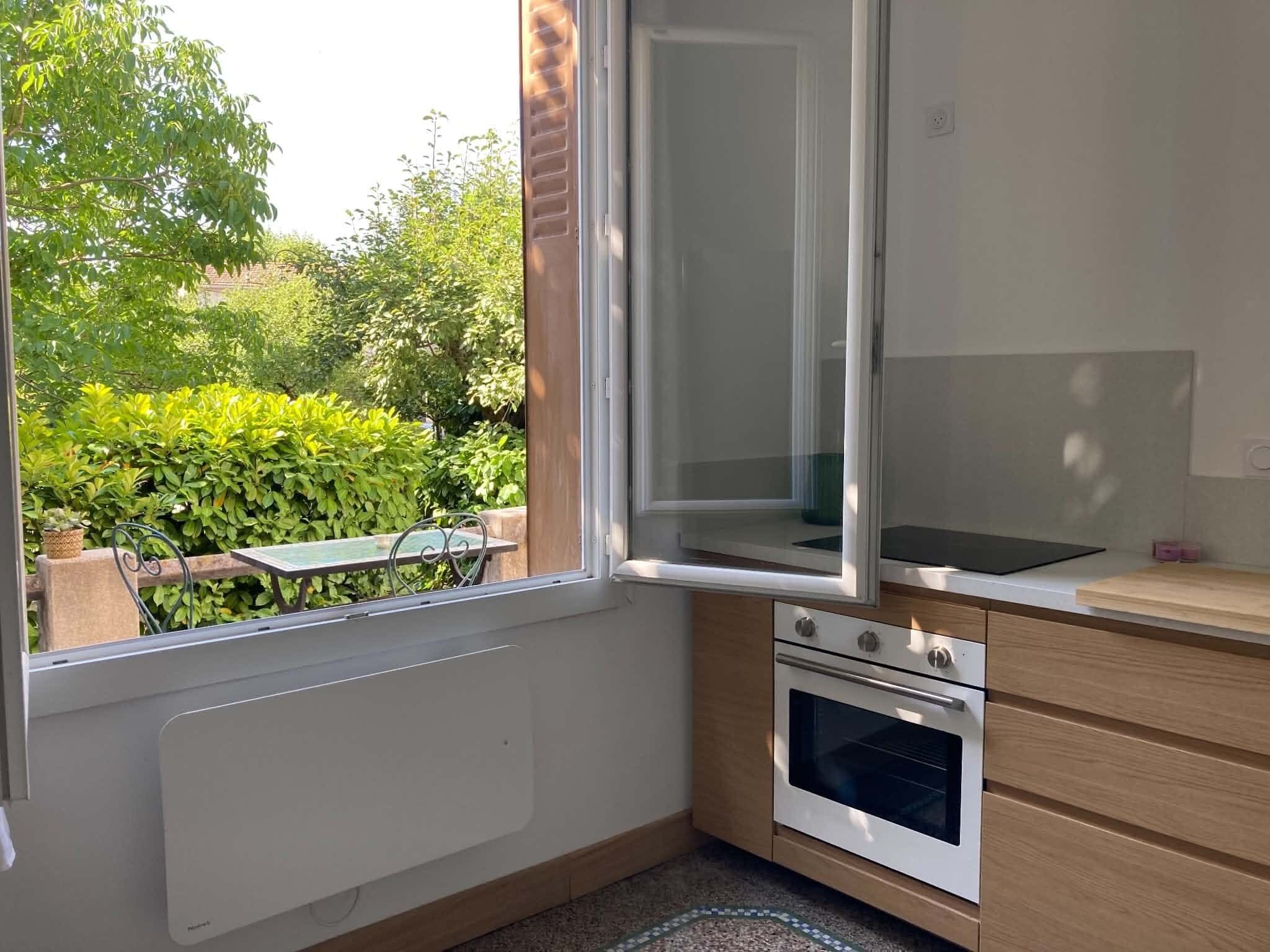 A kitchen with a window, a radiator, a countertop, and a built-in oven.