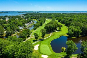 An aerial view of a golf course with a lake, surrounded by dense trees and residential areas. - Brand New Beach House | Sleeps 8 | Ocean Pines, MD (Berlin)