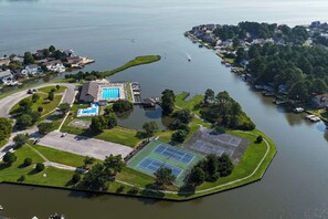 Eine Vogelperspektive eines Sees mit einem Anwesen, das einen Swimmingpool, Tennisplätze und einen Bootssteg beinhaltet.