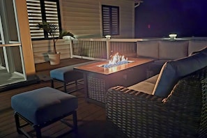 An outdoor seating area with a fire feature, cushioned seating, and a wooden deck. - Brand New Beach House | Sleeps 8 | Ocean Pines, MD (Berlin)