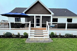 A two-story house with a front porch, a covered patio area, and a small garden. - Brand New Beach House | Sleeps 8 | Ocean Pines, MD (Berlin)