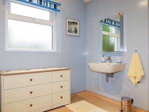 A bathroom with a white vanity, a sink, a mirror, a window, and a towel rack. - Brambleside Lodge (Truro)