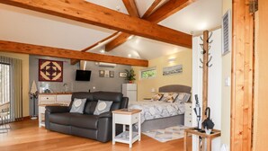 Una habitación acogedora con sofá, cama, una mesita y estructura de techo de madera.