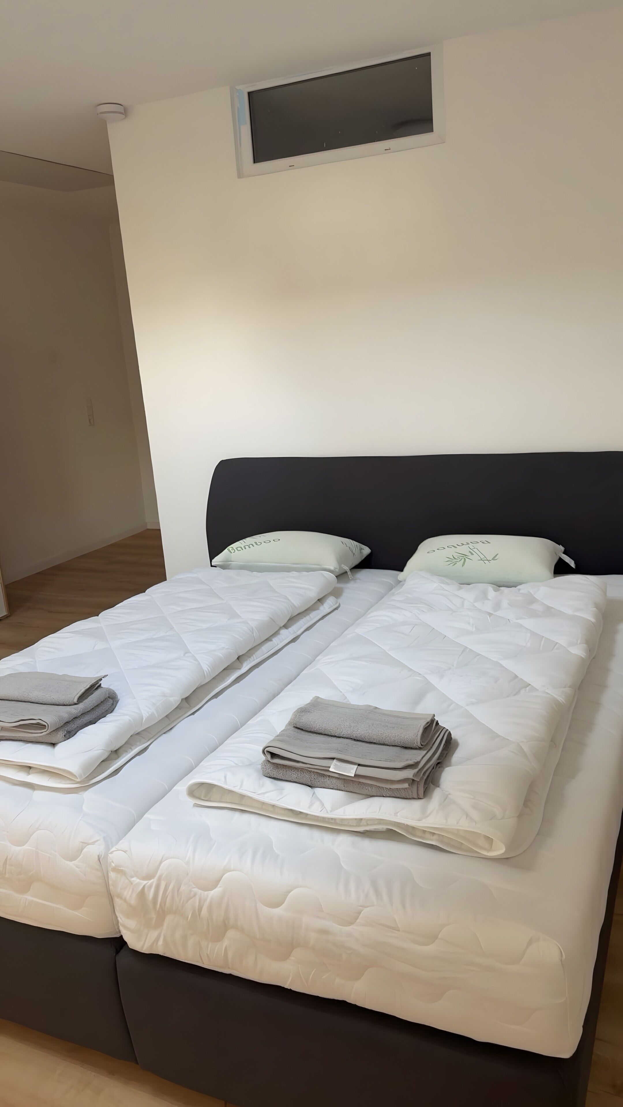 A double bed with a dark headboard, two pillows, and folded blankets.