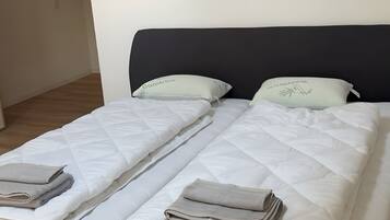 A double bed with a dark headboard, two pillows, and folded blankets.