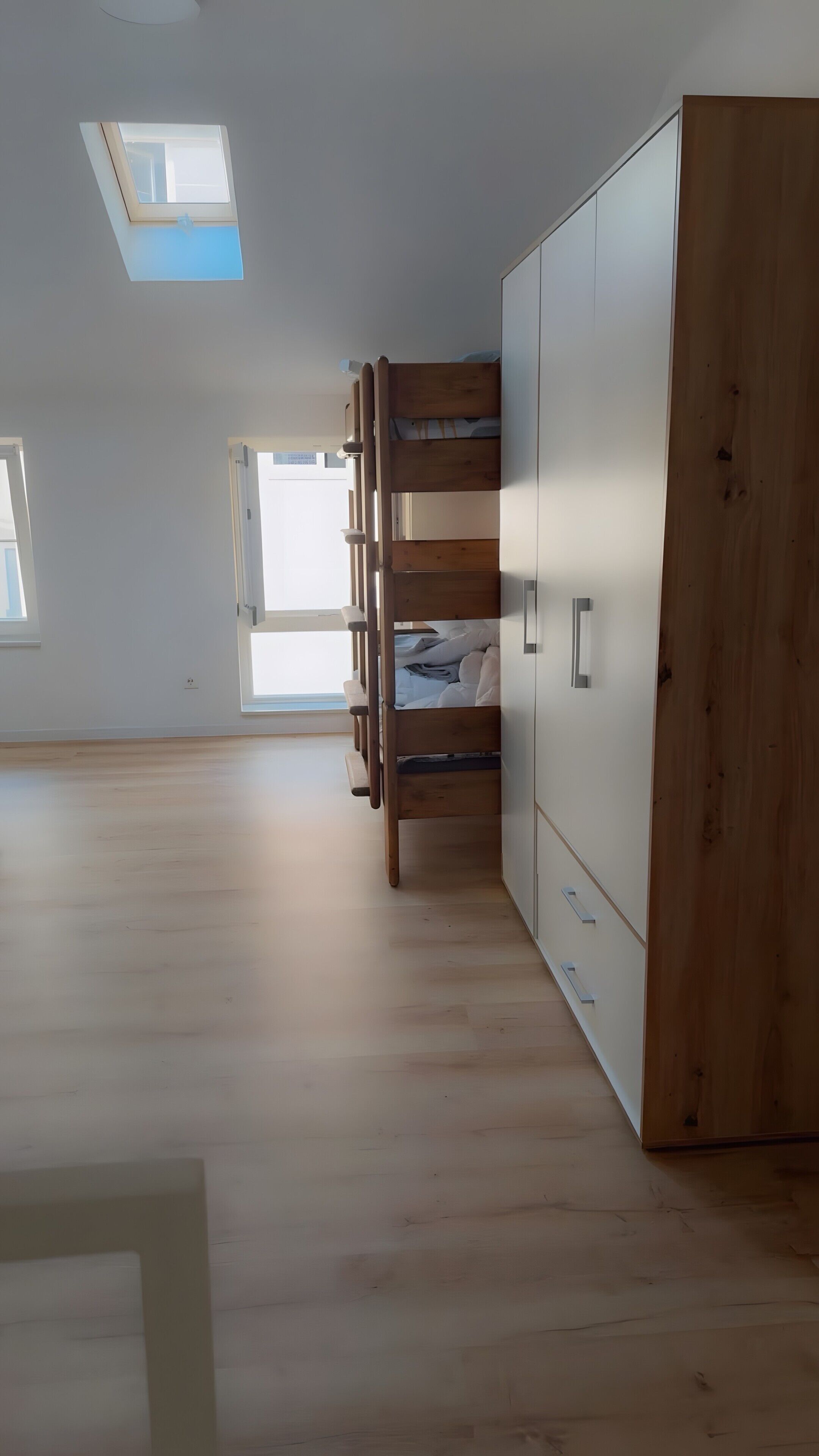 Quarto com beliche, guarda-roupa e claraboia.