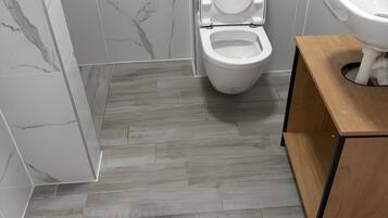 A bathroom with a toilet, a sink, and a wooden vanity.
