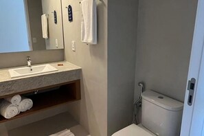 Ein Badezimmer mit Waschbecken, Spiegel, Handtuchhalter und Toilette.