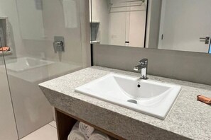 A modern bathroom with a rectangular sink, a glass shower enclosure, and a mirror above the sink. - Apartment Muro Alto (N. Sra. do Ó)