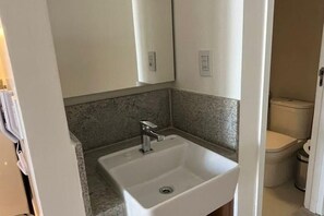 A bathroom with a white sink, a mirror, and a toilet. - Apartment Muro Alto (N. Sra. do Ó)