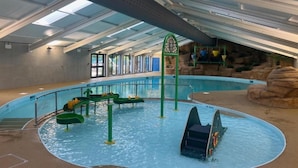 Ein Hallenbad mit Wasserrutschen und einer Felswand im Hintergrund.