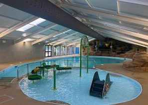 Una piscina interior con toboganes y un muro de roca de fondo.