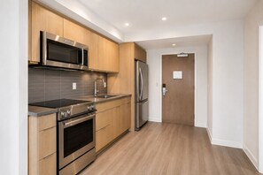 Eine moderne Küche mit Edelstahlgeräten, Holzschränken und einer gefliesten Spritzschutzwand.