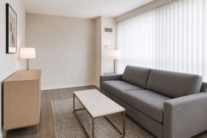 Ein modernes Wohnzimmer mit einem grauen Sofa, einem Holzkabinett, einem kleinen Tisch und zwei Wandleuchten.