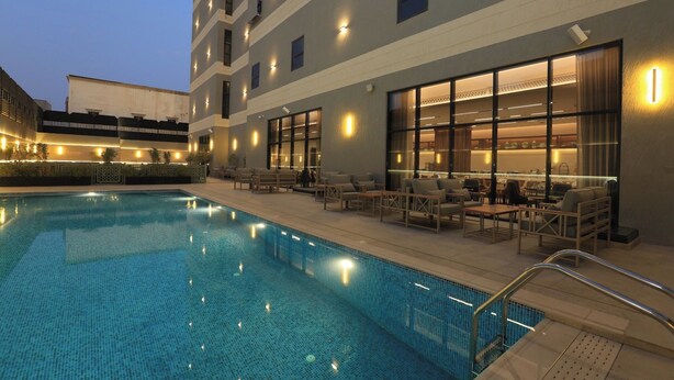 Ein Hotelpoolbereich mit einem klaren, blauen Pool, Liegestühlen und einer Bar mit Sitzgelegenheiten.