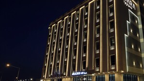 Ein mehrstöckiges Hotel mit beleuchteter Beschilderung, einem markanten Eingang und modernem architektonischem Design.