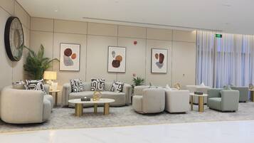 Een moderne lobby met een zithoek, een bijzettafeltje en abstracte kunst aan de muur.