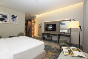A hotel room with a bed, a desk, a television, a mirror, and a lamp. - Azara Hotel (Riyadh)