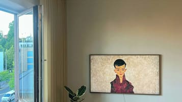 Una habitación con un radiador, una planta en maceta, un cuadro en la pared y una ventana con cortinas.