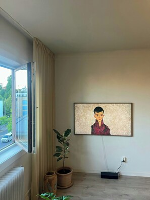 A room with a radiator, a potted plant, a painting on the wall, and a window with curtains. - Top-floor flat with views over Oslo and Østmarka (Oslo)