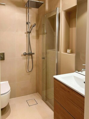 A modern bathroom with a glass-enclosed shower, a white sink, and a wooden vanity. - Top-floor flat with views over Oslo and Østmarka (Oslo)