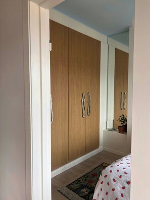 A bedroom with a large wardrobe, a bed with a patterned bedspread, and a small potted plant on a nightstand. - Top-floor flat with views over Oslo and Østmarka (Oslo)