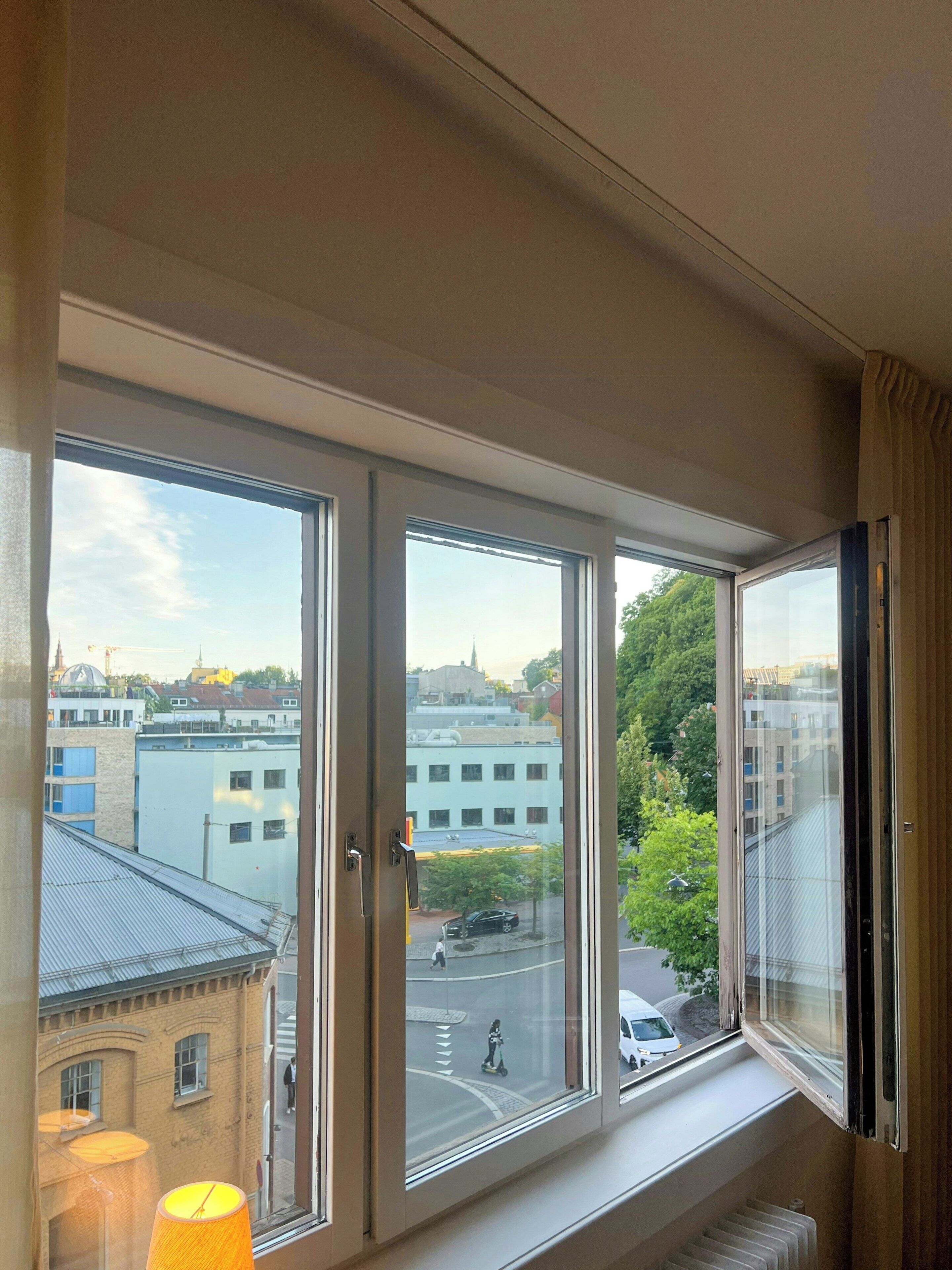 A room with a large window overlooking a cityscape, including buildings and a street.