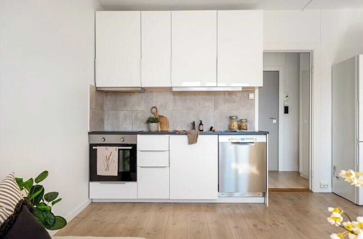 Une cuisine moderne avec des meubles blancs, un four encastré et un lave-vaisselle.