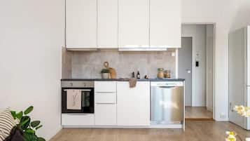 Una cocina moderna con armarios blancos, horno integrado y lavavajillas.