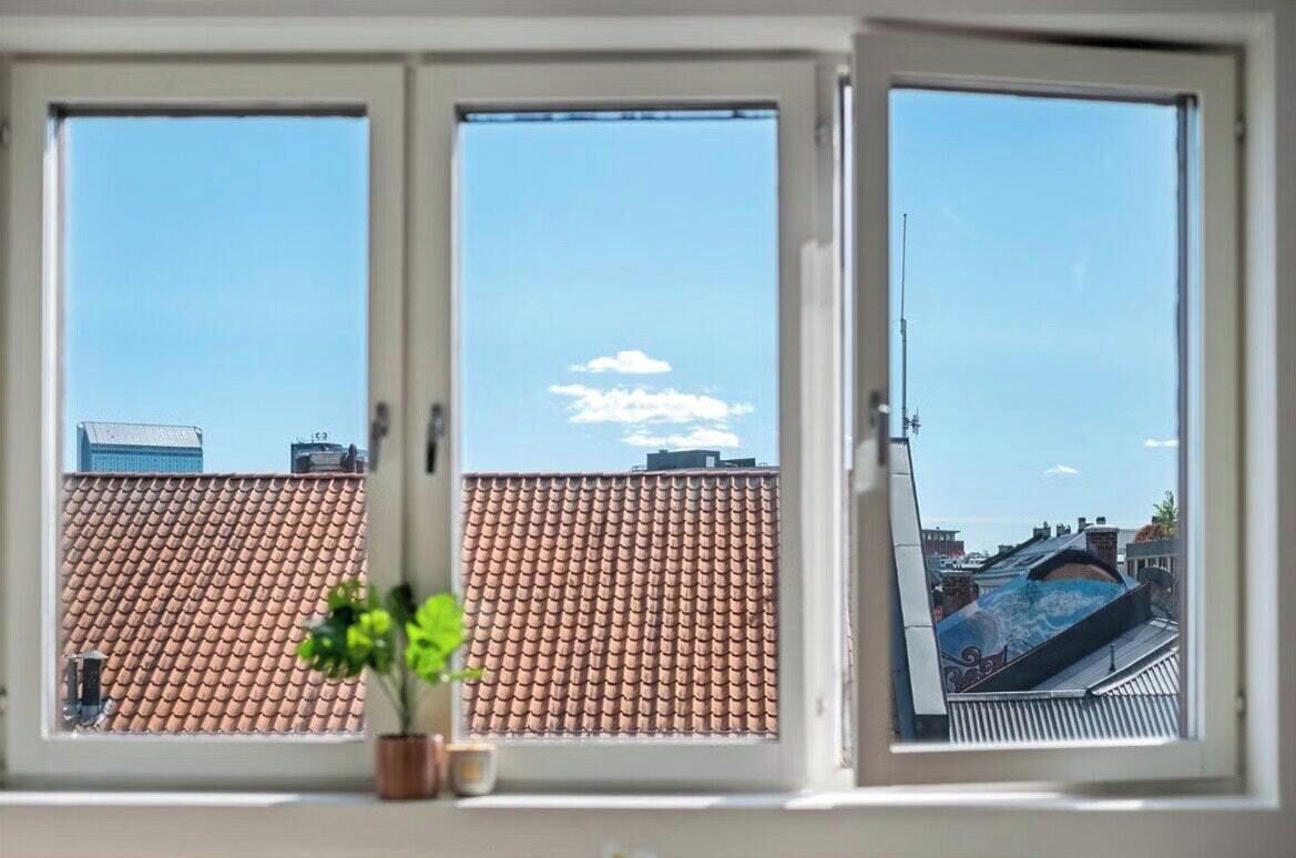 A window with a view of a tiled roof and a clear sky.
