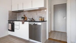 Una cocina moderna con armarios blancos, un lavavajillas de acero inoxidable y un horno empotrado.