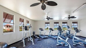 A gym with treadmills, elliptical machines, and a ceiling fan.