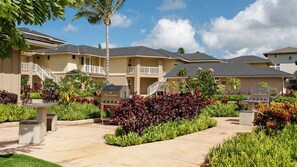 Hotel com várias varandas, churrasqueiras ao ar livre e um jardim bem cuidado com diversas plantas.