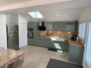 A compact kitchen with a built-in oven, a sink, and a dining area with a table and chairs. - Villa for 9 people near La Gautrelle Beach, ideally located (Saint-Georges-d'Oléron)