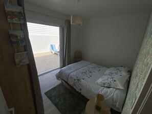 A bedroom with a bed, a chair, a lamp, and a view of the outside. - Villa for 9 people near La Gautrelle Beach, ideally located (Saint-Georges-d'Oléron)