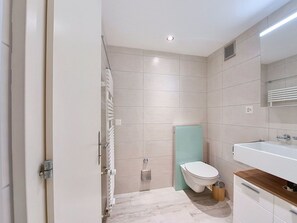 Une salle de bain moderne équipée de toilettes, d’un lavabo et d’une zone douche.