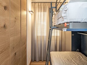 Ein Etagenbett mit Matratze und einer Leiter, Holzwände und einem Vorhang.