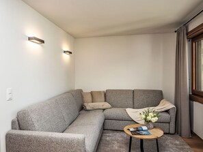 Ein modernes Wohnzimmer mit einem Ecksofa, einem kleinen runden Couchtisch und zwei Wandleuchten.