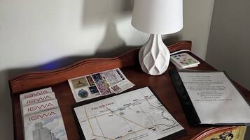 A room with a wooden desk, a map, a framed picture, and a white lamp.