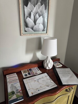 A room with a wooden desk, a map, a framed picture, and a white lamp.