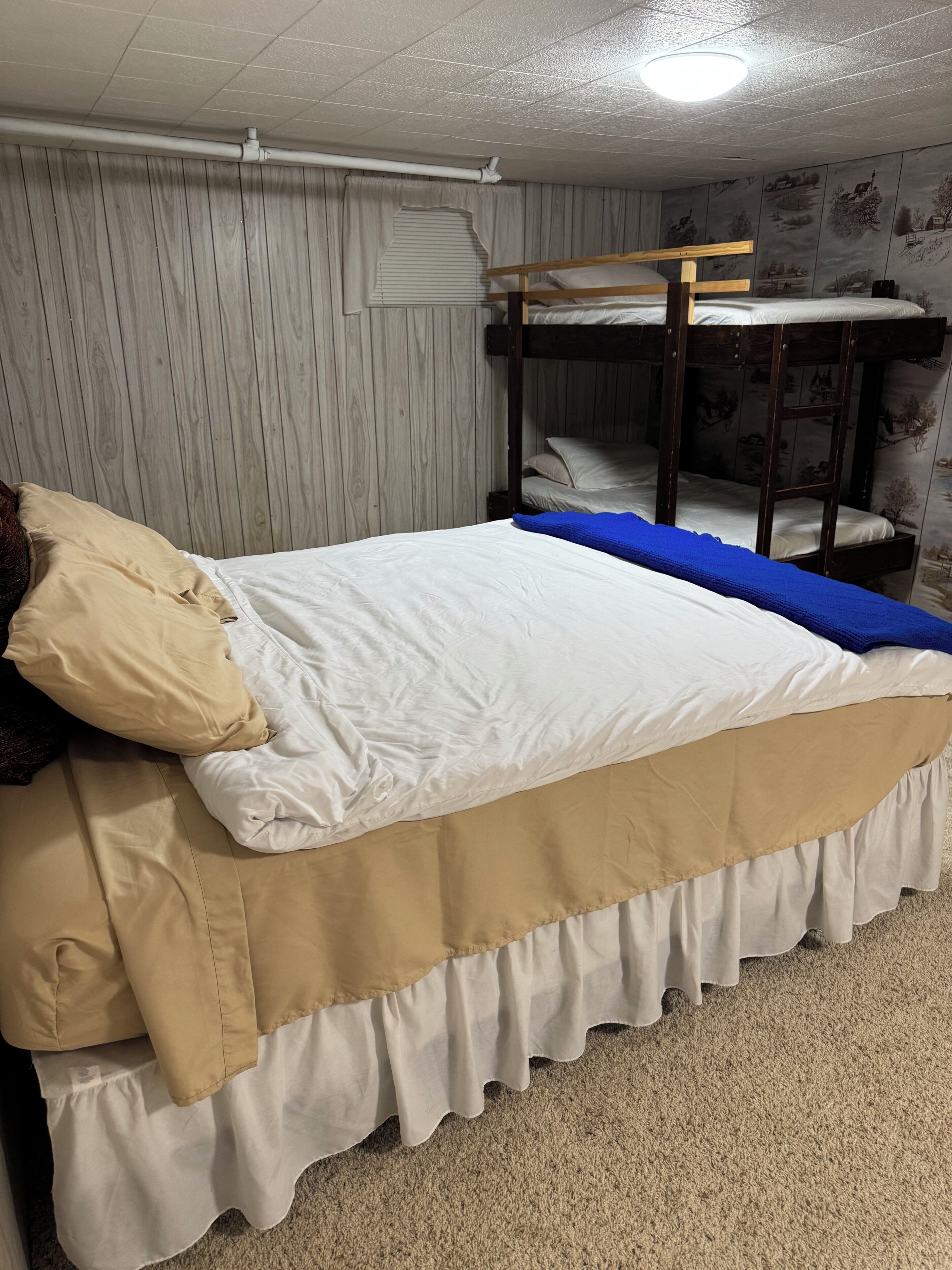 A bunk bed with a white mattress and a beige skirted bed base.