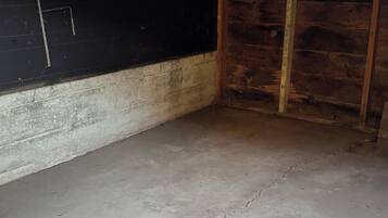 A room with a concrete floor, wooden walls, and a window.
