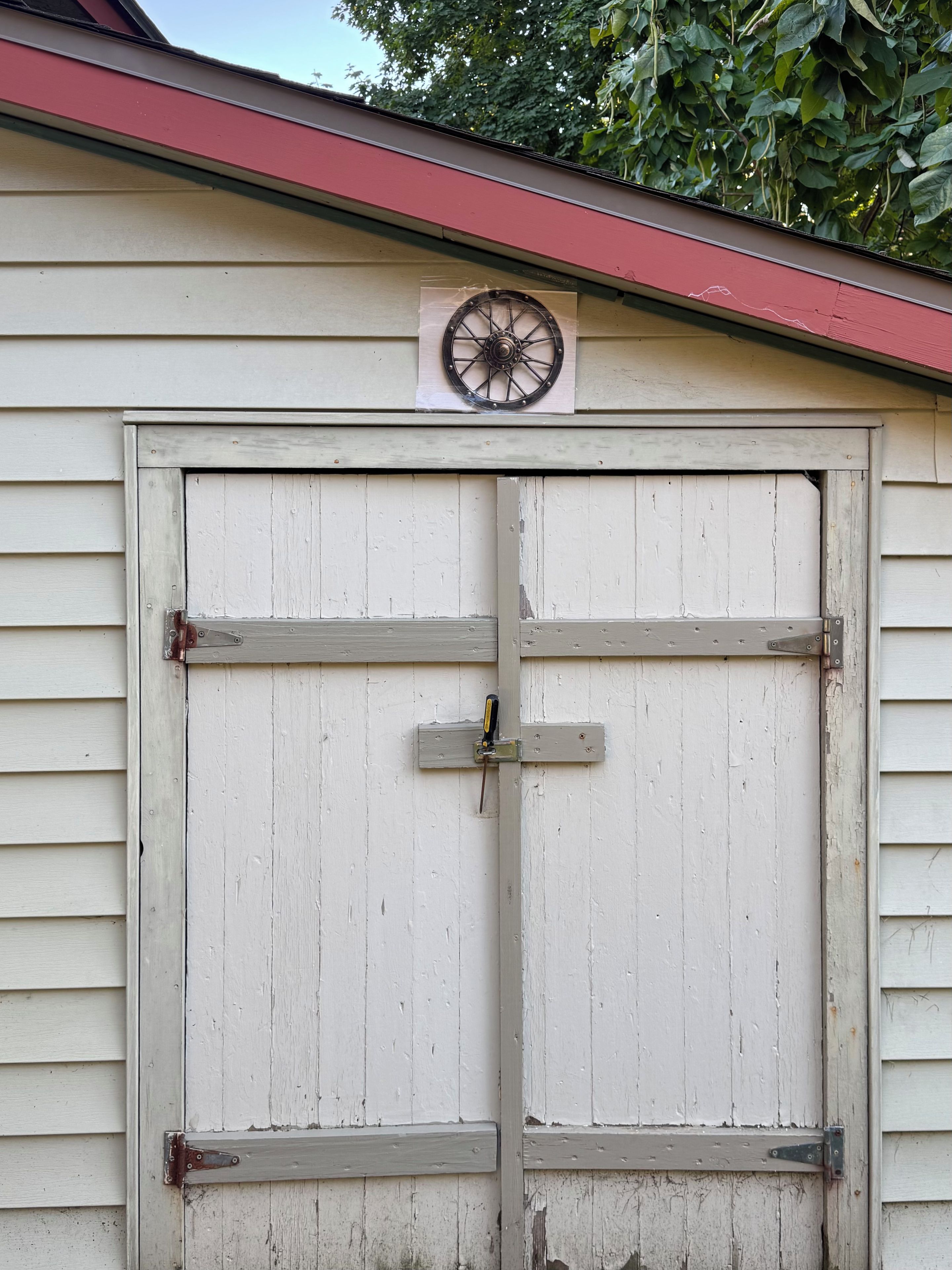 A white wooden garage door with a metal handle and a small wheel.